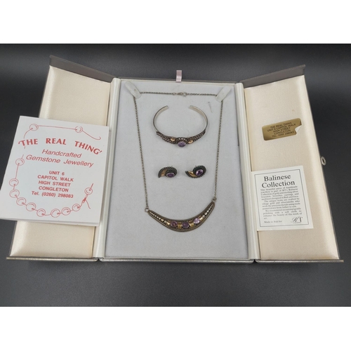 185 - A cased 925 silver and amethyst three piece jewellery set comprising necklace, bracelet and pair of ... 