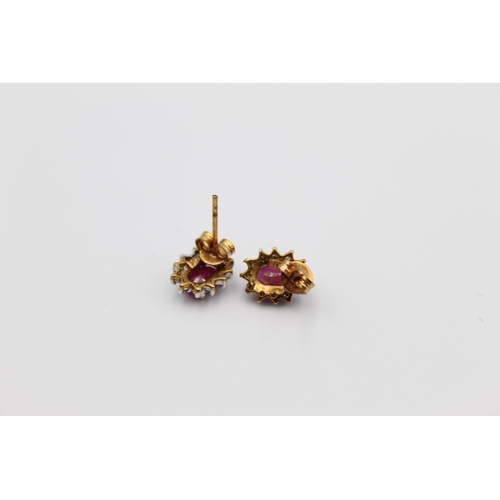 21 - A pair of 9ct gold ruby and diamond halo stud earrings - approx. gross weight 1.3g