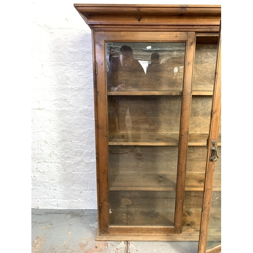 666 - A large Victorian stained pine free standing bookcase with two glazed doors and three internal shelv... 