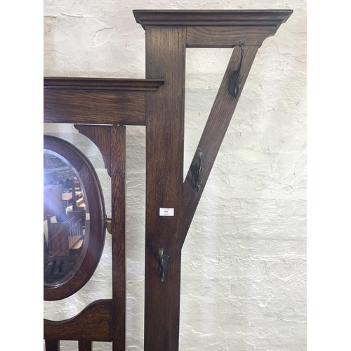 695 - An Art Deco oak hall stand with centre bevelled mirror, six coat hooks and original drip trays - app... 