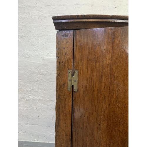 708 - A Georgian oak bow front wall mountable corner cabinet with brass 'H' hinges and three internal shel... 