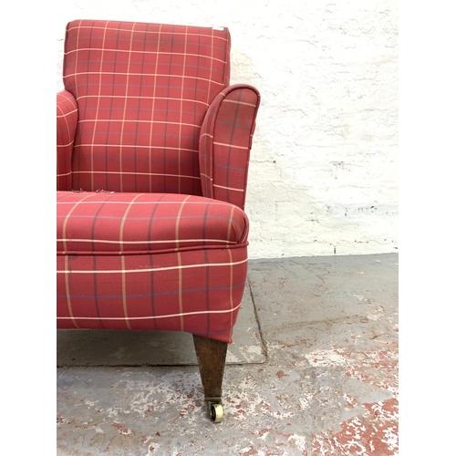 714 - An Edwardian red upholstered library armchair on brass castors