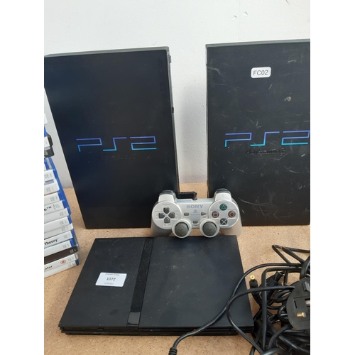 1072 - A box containing three Sony PlayStation 2 consoles, two original and one slimline with black and sil... 