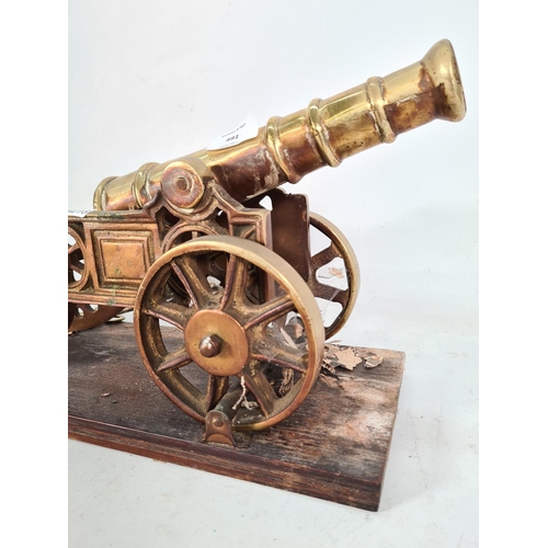 491 - A vintage brass ornamental cannon on wooden plinth - approx. 23cm high x 15cm wide x 45cm deep