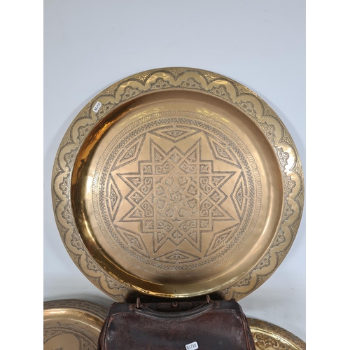 492 - Four items, three Middle Eastern brass wall chargers - the largest approx. 64cm diameter and one vin... 