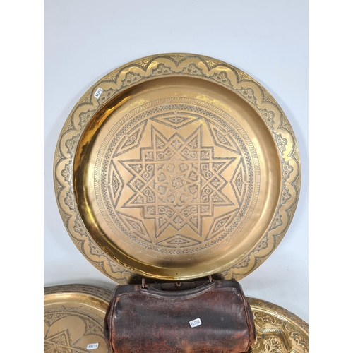 492 - Four items, three Middle Eastern brass wall chargers - the largest approx. 64cm diameter and one vin... 