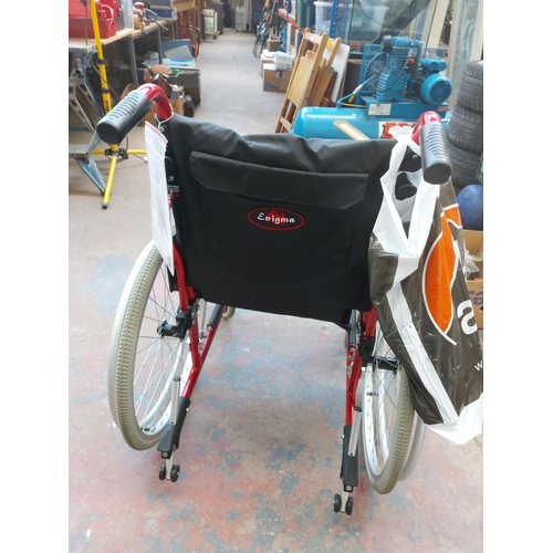 1208 - A black and red Enigma folding self propelled wheelchair with footrests and instruction manual