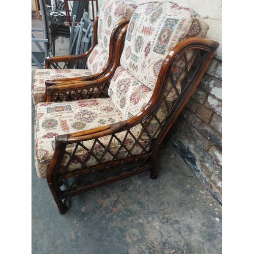 1222 - A pair of dark cane conservatory armchairs with multi coloured upholstery