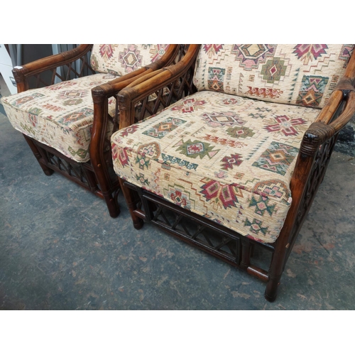 1222 - A pair of dark cane conservatory armchairs with multi coloured upholstery