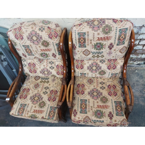 1222 - A pair of dark cane conservatory armchairs with multi coloured upholstery