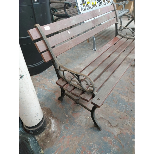 1228 - A wooden slatted two seater garden bench on cast iron supports