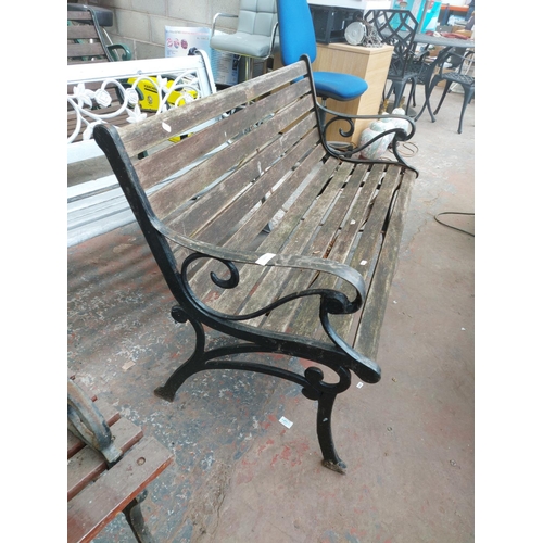 1229 - A wooden slatted two seater garden bench on cast iron supports