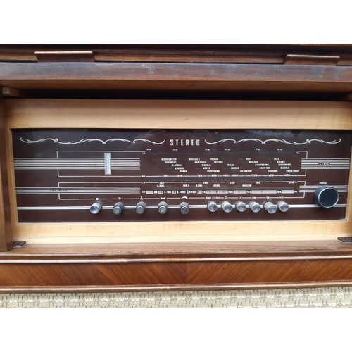 1128 - A polished walnut veneered stereo radiogram fitted with Garrard 1025 four speed auto changer turntab... 