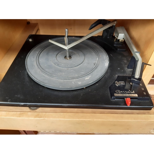 1128 - A polished walnut veneered stereo radiogram fitted with Garrard 1025 four speed auto changer turntab... 