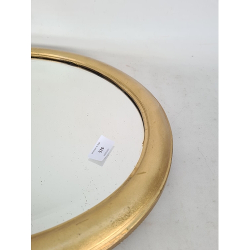 576 - A vintage gilt framed bevelled edge oval wall mirror - approx. 57cm x 46cm