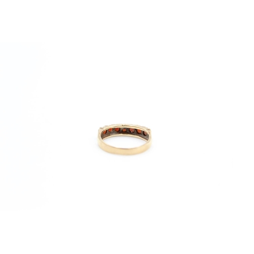 74 - A 9ct gold garnet set half eternity ring, size O - approx. gross weight 2.7 grams