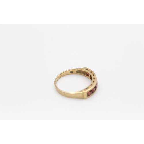 141 - A 9ct gold garnet band ring, size M½ - approx. gross weight 2.1 grams