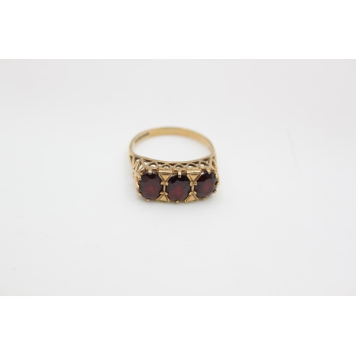 84 - A 9ct gold garnet trilogy dress ring, size O ½ - approx. gross weight 3.2 grams