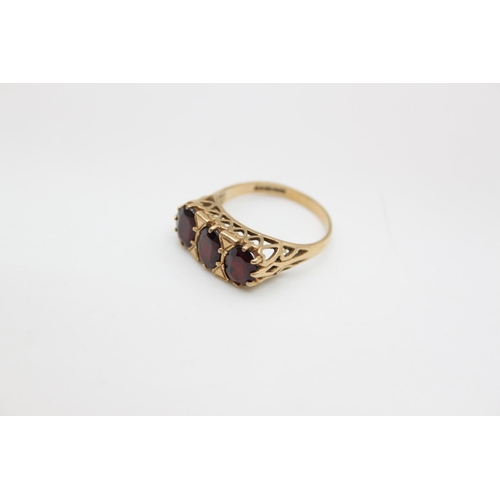 84 - A 9ct gold garnet trilogy dress ring, size O ½ - approx. gross weight 3.2 grams