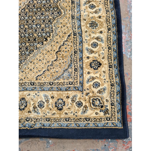 1099 - A late 20th century Turkish Prestige blue and ivory rug - approx. 120cm wide x 170cm long