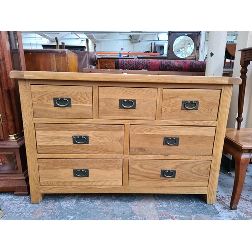 1103 - A modern light oak chest of seven drawers - approx. 85cm high x 130cm wide x 47cm deep