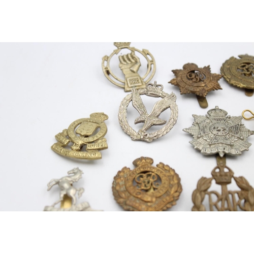 100 - Fifteen assorted vintage military cap badges to include Royal Armored Corps, South African Border et... 