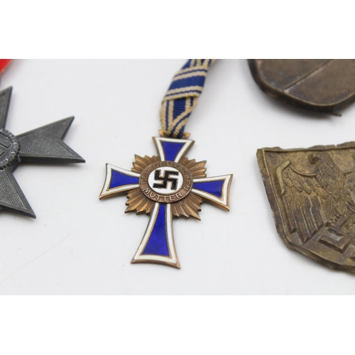 116 - A collection of WWII German medals & pith helmet badges to include bronze Mother's Cross, Merit Cros... 