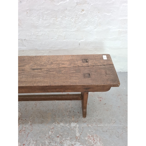 1003 - An early 20th century oak school bench - approx. 47cm high x 242cm long x 25cm deep