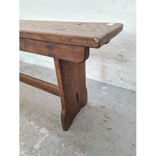 1003 - An early 20th century oak school bench - approx. 47cm high x 242cm long x 25cm deep