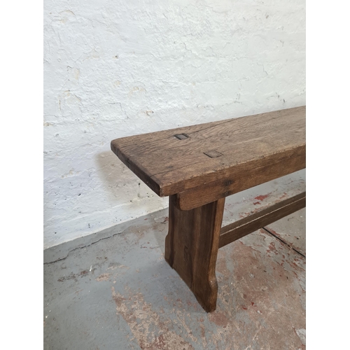 1003 - An early 20th century oak school bench - approx. 47cm high x 242cm long x 25cm deep