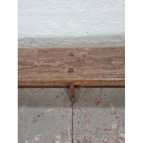 1004 - An early 20th century oak school bench - approx. 47cm high x 242cm long x 25cm deep