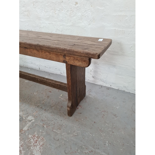 1004 - An early 20th century oak school bench - approx. 47cm high x 242cm long x 25cm deep