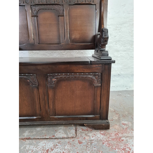 1014 - An oak monks bench with carved lion design arms and lower storage  - approx. 100cm high x 100cm wide... 