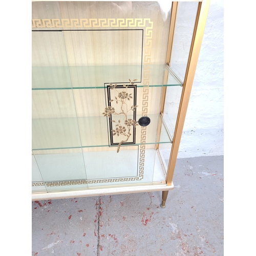 1033 - A mid 20th century white melamine display cabinet with two glass sliding doors, two internal glass s... 