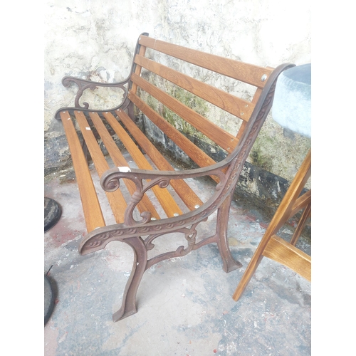 1225 - A wooden slatted three seater garden bench with ornate cast iron ends