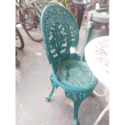 1229 - Three items, one round cast aluminium ornate patio table and two matching chairs