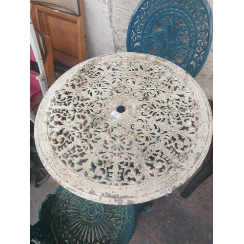 1229 - Three items, one round cast aluminium ornate patio table and two matching chairs