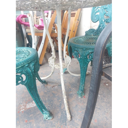 1229 - Three items, one round cast aluminium ornate patio table and two matching chairs