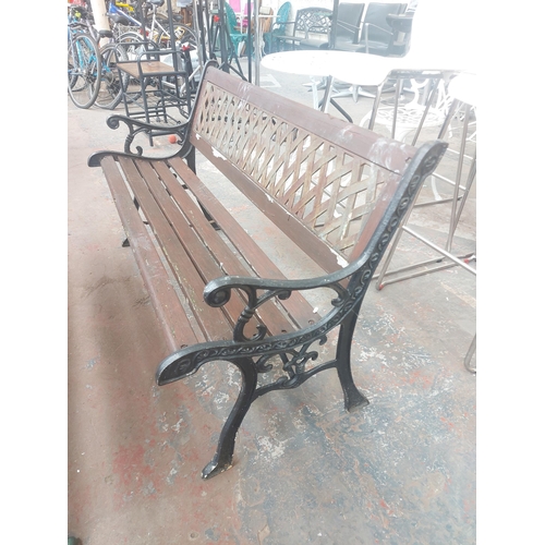 1239 - A wooden slatted three seater garden bench with ornate cast iron supports and back