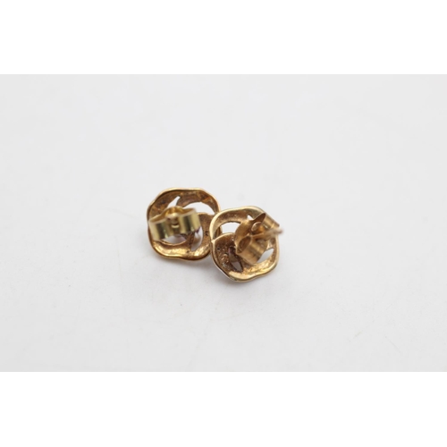 94 - Two pairs of 9ct gold gemstone and diamond twirl stud earrings, one ruby and one amethyst - approx. ... 
