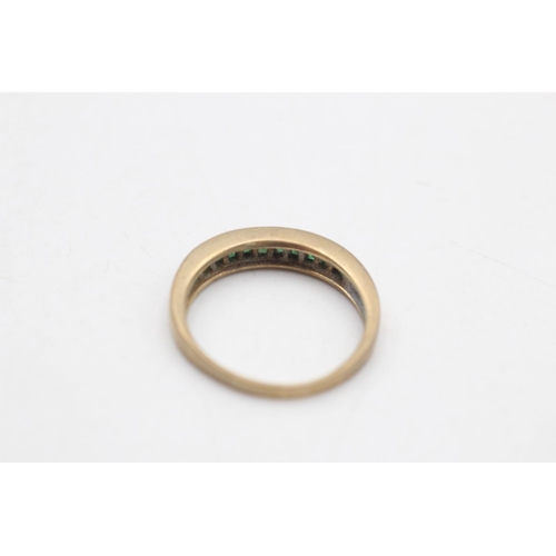 97 - A 9ct gold emerald channel set half eternity ring, size P - approx. gross weight 2.6 grams