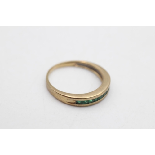 97 - A 9ct gold emerald channel set half eternity ring, size P - approx. gross weight 2.6 grams