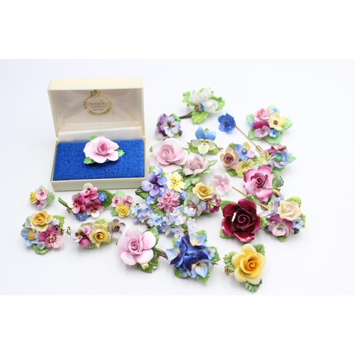 113 - Twenty five pieces of porcelain jewellery to include brooches, pins etc.