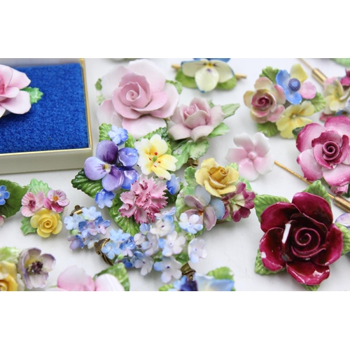 113 - Twenty five pieces of porcelain jewellery to include brooches, pins etc.
