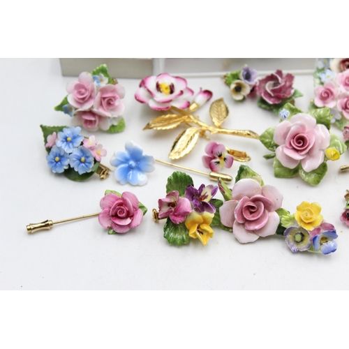 114 - Twenty five pieces of porcelain jewellery to include brooches, pins etc.