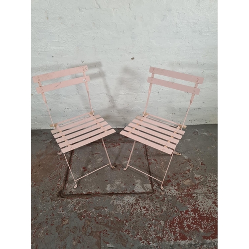 1100 - A pair of pink metal folding patio chairs