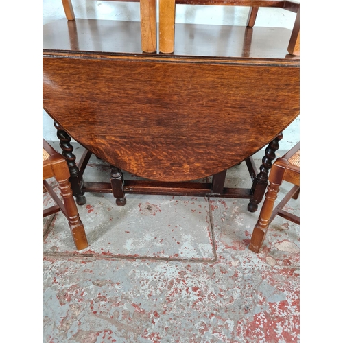 1139 - A vintage oak drop leaf gate leg dining table with barley twist supports and four rush seated dining... 