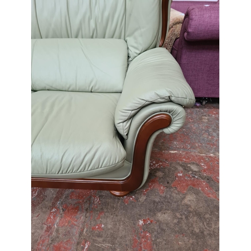 1165 - A lime green leather and mahogany two piece lounge suite comprising armchair and two seater sofa