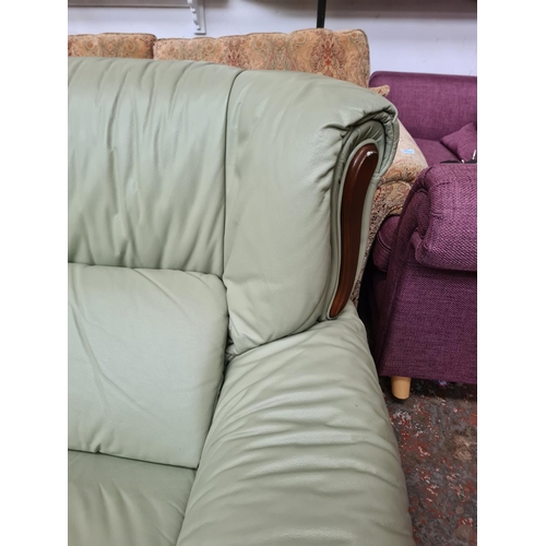 1165 - A lime green leather and mahogany two piece lounge suite comprising armchair and two seater sofa