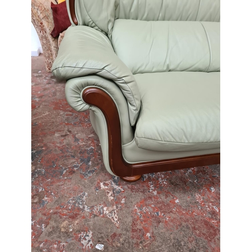 1165 - A lime green leather and mahogany two piece lounge suite comprising armchair and two seater sofa